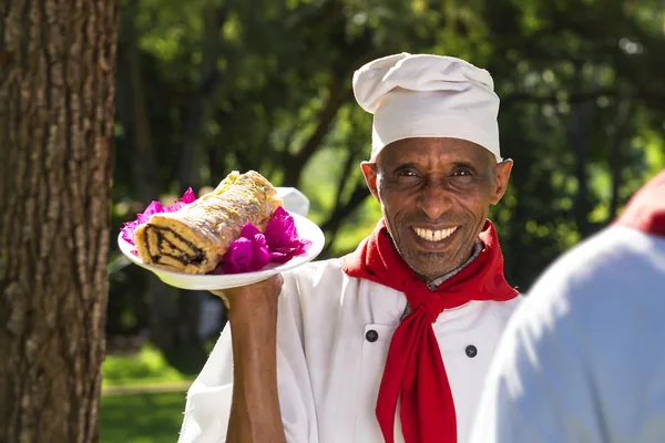 Smiling chef presenting a plate of pastries