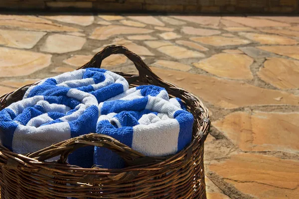 Basket of pool towels on warm stone